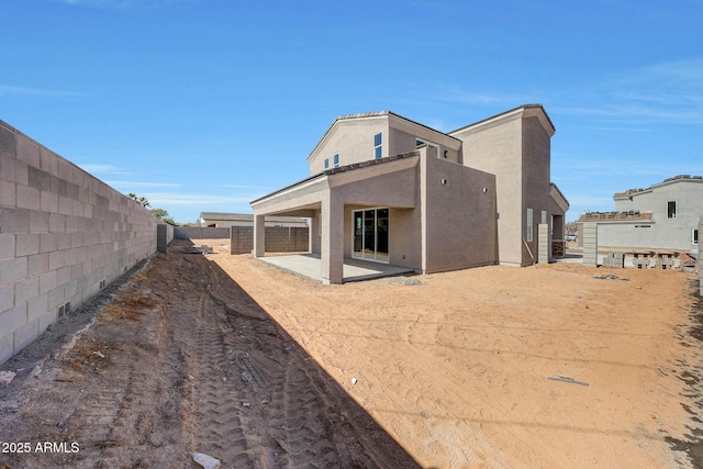 rear view of property with a fenced backyard, a patio, and stucco siding