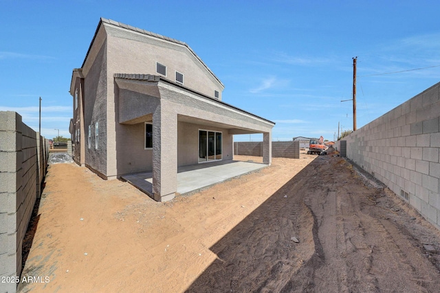 rear view of property with a patio area, a fenced backyard, and stucco siding