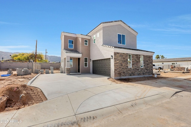 view of front of house with stucco siding, an attached garage, a mountain view, stone siding, and driveway