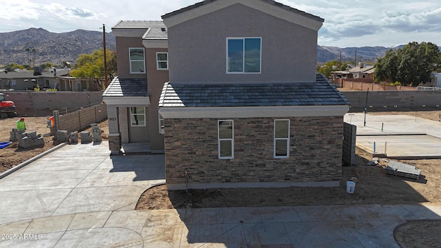 rear view of house featuring a patio area, fence, a mountain view, and stucco siding