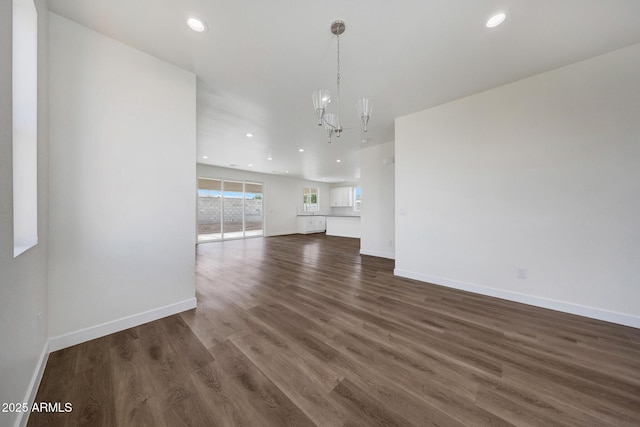 interior space with dark wood-type flooring, recessed lighting, baseboards, and an inviting chandelier