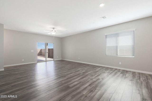 spare room featuring a ceiling fan, visible vents, baseboards, and wood finished floors