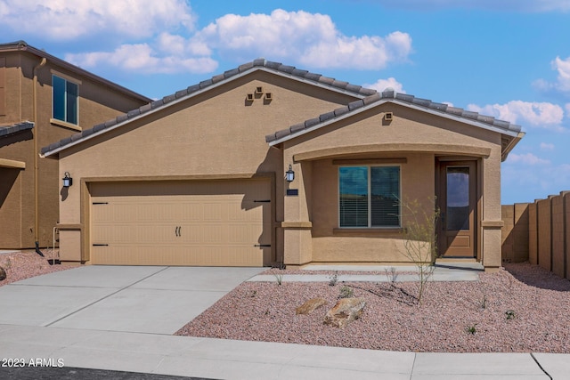 view of front facade with a tile roof, stucco siding, fence, a garage, and driveway