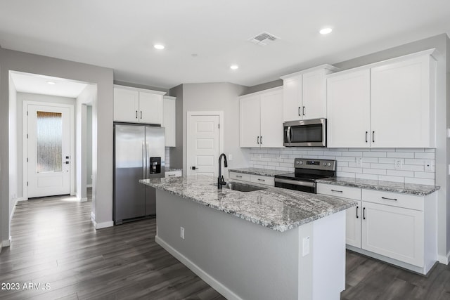 kitchen with stainless steel appliances, an island with sink, white cabinetry, and decorative backsplash