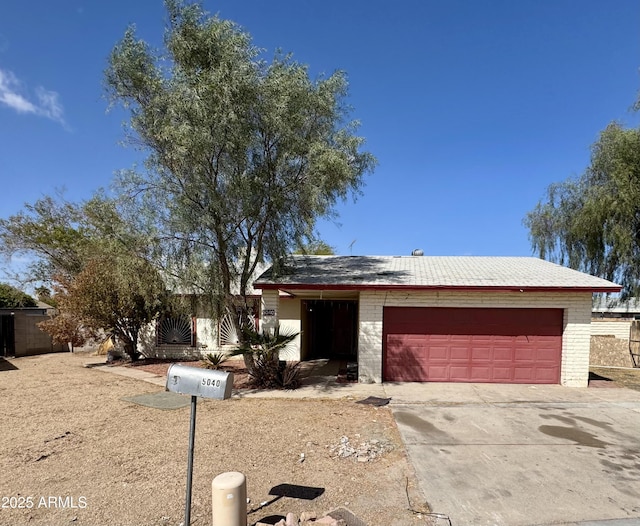 view of front of property with concrete driveway, an attached garage, and an outbuilding