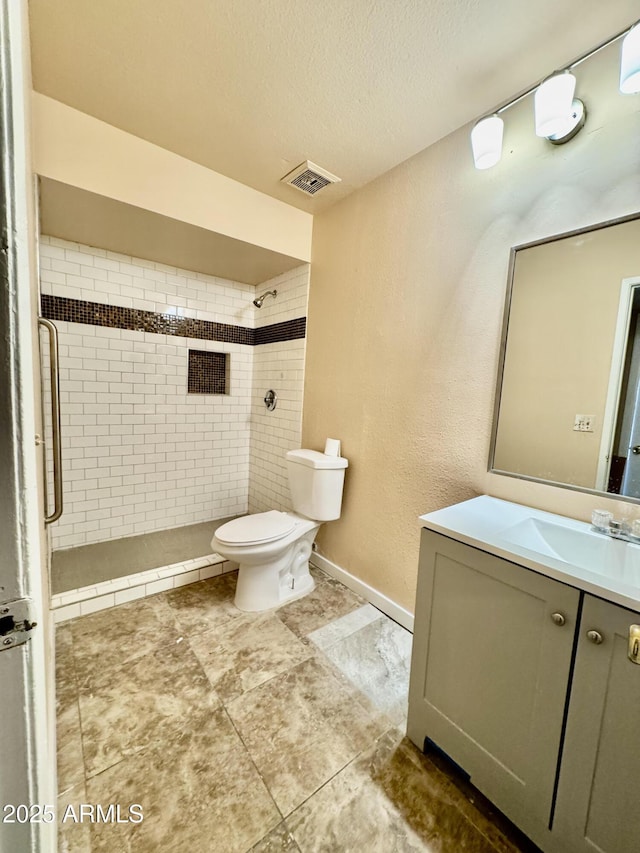 full bath featuring visible vents, toilet, a textured ceiling, a tile shower, and vanity