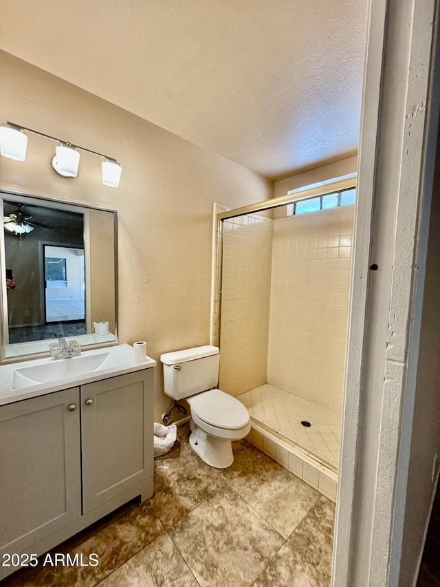 bathroom featuring toilet, a stall shower, vanity, and a textured ceiling