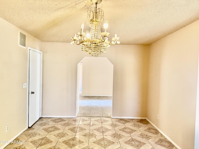 spare room with baseboards, visible vents, arched walkways, a textured ceiling, and a notable chandelier