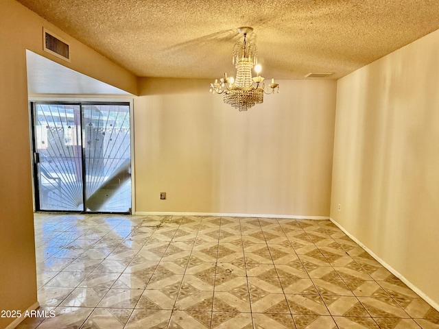 spare room with a notable chandelier, visible vents, a textured ceiling, and baseboards