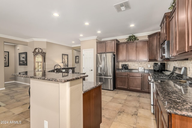 kitchen featuring decorative backsplash, stainless steel appliances, a kitchen island with sink, and dark stone counters