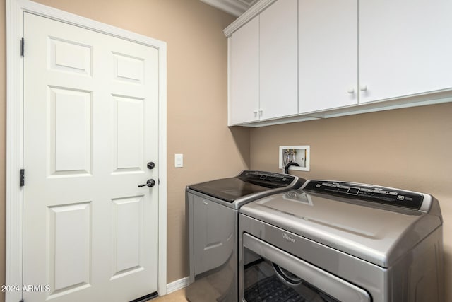 clothes washing area featuring cabinets and washing machine and clothes dryer