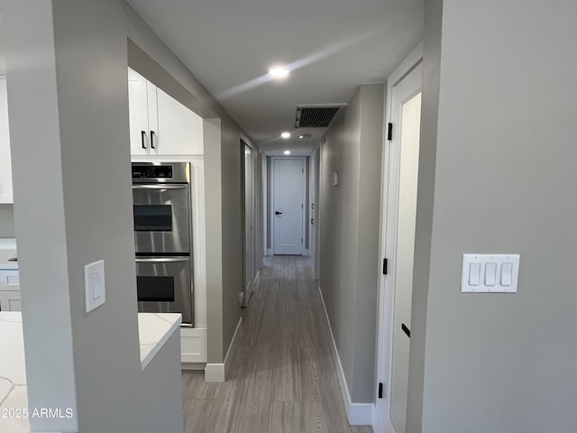 corridor with baseboards, recessed lighting, light wood finished floors, and visible vents