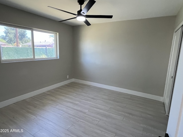 empty room featuring baseboards, ceiling fan, and light wood finished floors