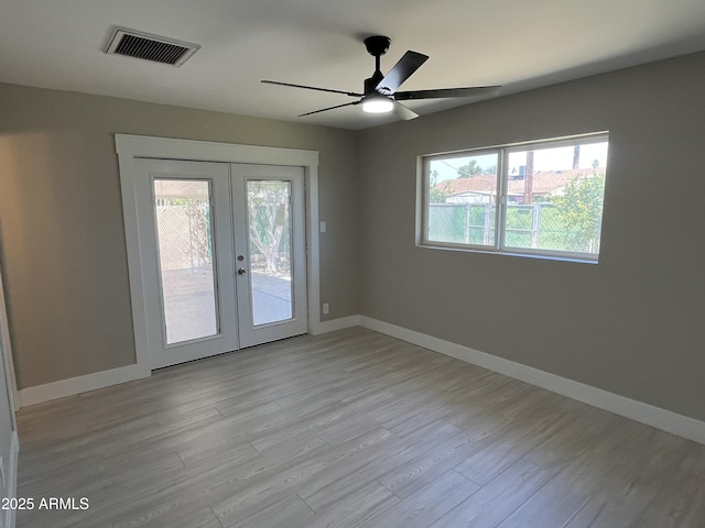 unfurnished room with a ceiling fan, french doors, visible vents, light wood-type flooring, and baseboards