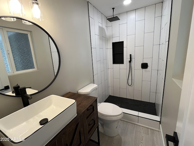 bathroom featuring vanity, recessed lighting, toilet, and tiled shower