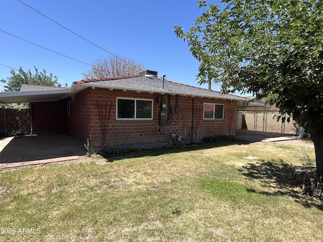 view of side of property with brick siding, fence, a yard, and an attached carport