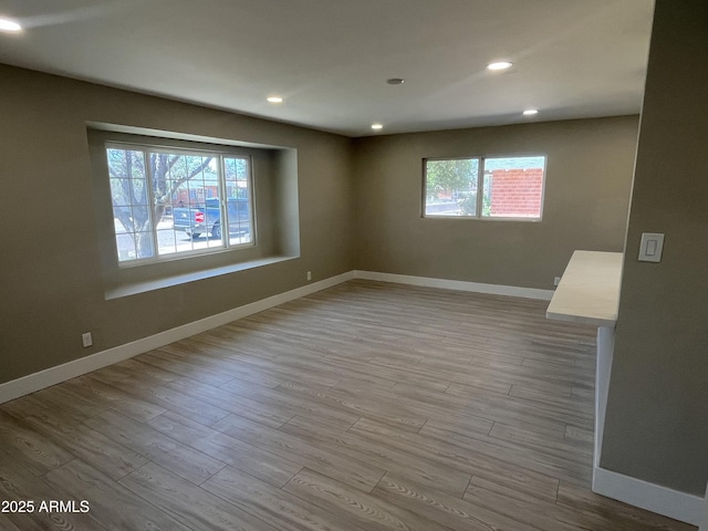 empty room featuring baseboards, a healthy amount of sunlight, and wood finished floors