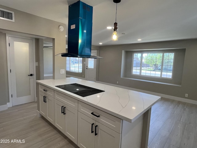 kitchen with light wood-style floors, island exhaust hood, black electric stovetop, and visible vents