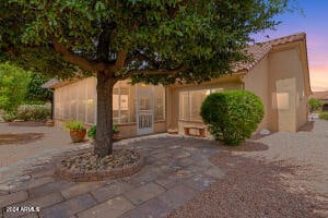 back house at dusk with a sunroom and a patio area