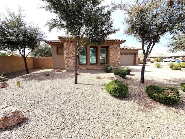 view of front of home featuring stone siding, an attached garage, a tile roof, and fence