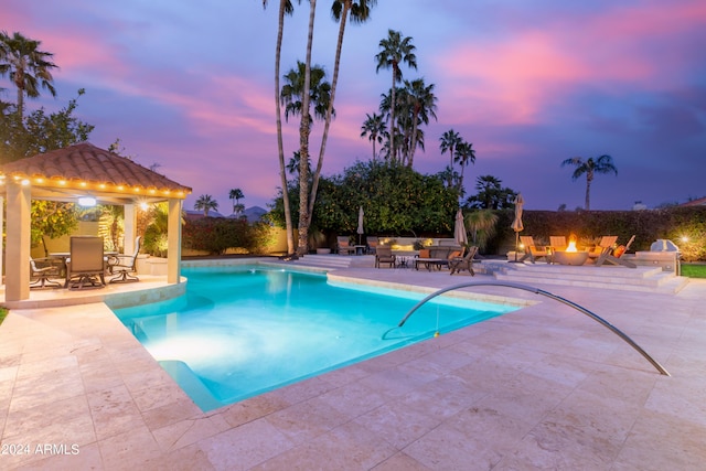 10658 E Cinnabar Ave, Scottsdale, AZ 85258 - pool at dusk with a patio, outdoor dining space, a fire pit, a gazebo, and an outdoor pool