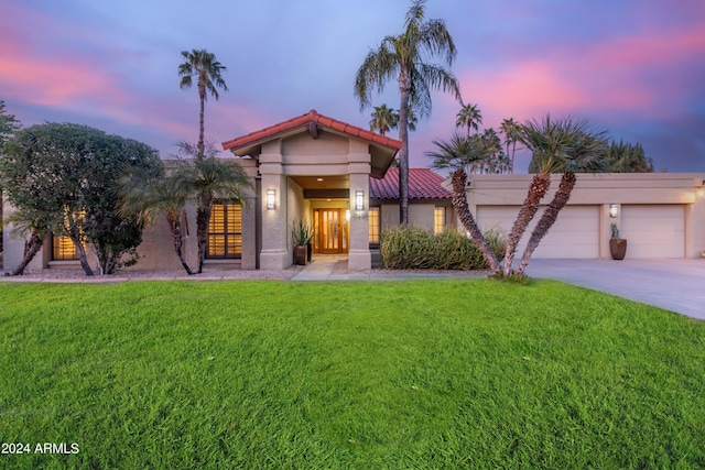 10658 E Cinnabar Ave, Scottsdale, AZ 85258 - mediterranean / spanish house featuring an attached garage, driveway, a tile roof, stucco siding, and a lawn