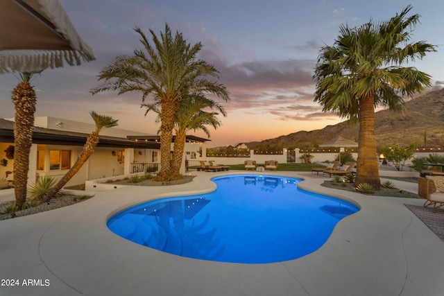 pool at dusk with a patio area and a mountain view