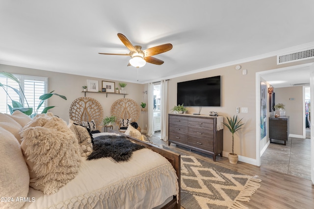 bedroom with ceiling fan, hardwood / wood-style floors, connected bathroom, ornamental molding, and a walk in closet