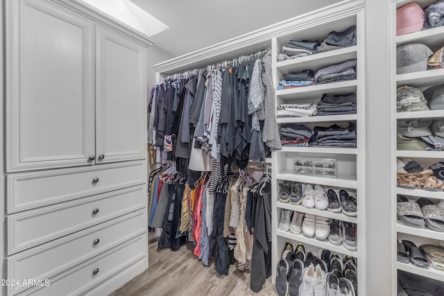 walk in closet with light hardwood / wood-style flooring