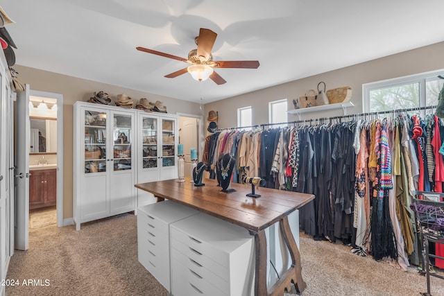 walk in closet with light carpet, ceiling fan, and sink