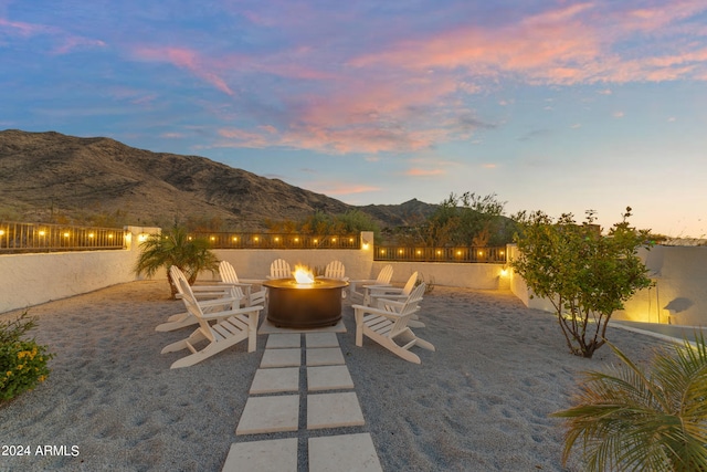 patio terrace at dusk featuring an outdoor fire pit and a mountain view