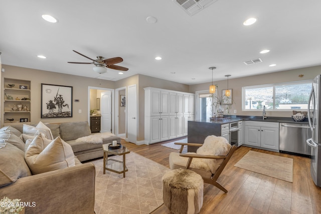 living room with light hardwood / wood-style floors, sink, and ceiling fan