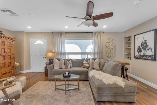 living room featuring ceiling fan, light wood-type flooring, and built in features