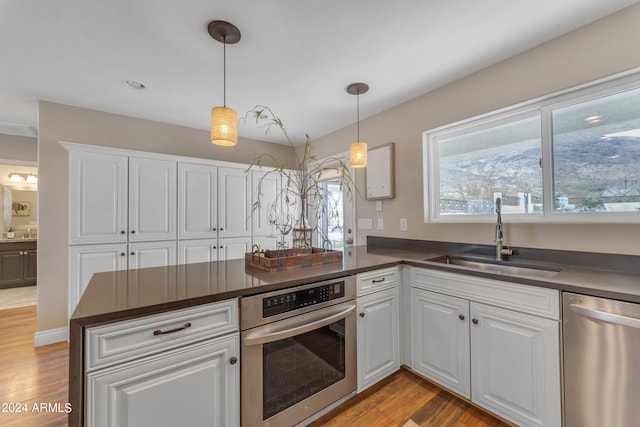 kitchen with sink, white cabinetry, kitchen peninsula, and stainless steel appliances