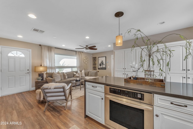 kitchen featuring decorative light fixtures, white cabinetry, light hardwood / wood-style flooring, and stainless steel oven