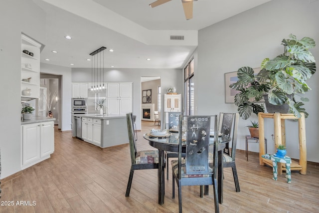 dining area with light hardwood / wood-style floors and ceiling fan