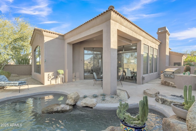 rear view of house featuring a patio and an outdoor kitchen