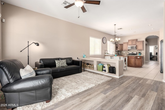 1333 W Deer Creek Rd, Phoenix, AZ 85045 - living room featuring visible vents, arched walkways, light wood-style floors, and ceiling fan with notable chandelier