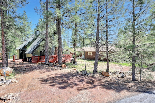 17455 S San Carlos Dr, Munds Park, AZ 86017 - view of front facade with a wooden deck, a chimney, and board and batten siding