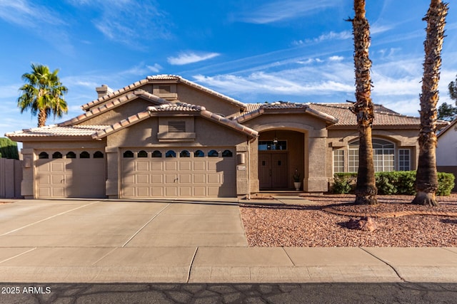 mediterranean / spanish-style home featuring a garage, driveway, a tile roof, and stucco siding