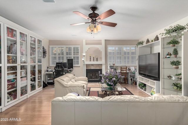 living area featuring light wood-style floors, a fireplace, and ceiling fan