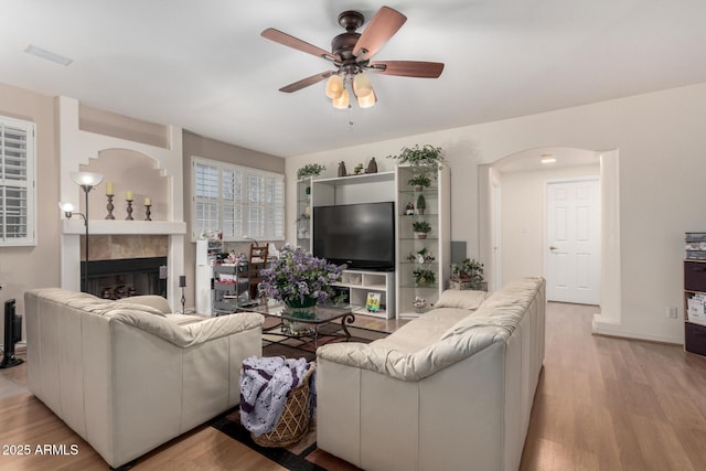 living area with light wood finished floors, visible vents, a ceiling fan, and a tile fireplace