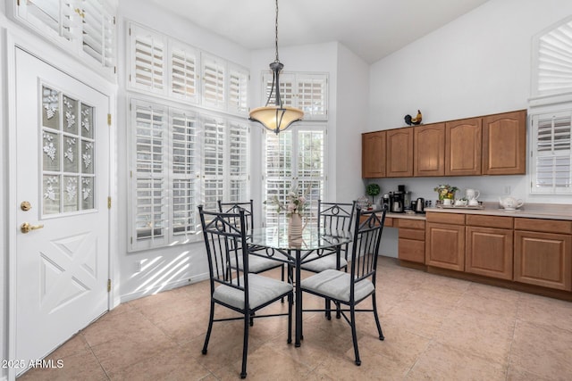 dining area featuring light tile patterned floors, a high ceiling, and baseboards