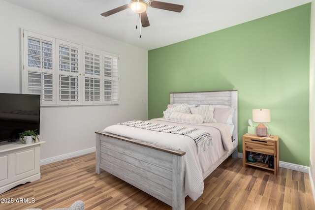 bedroom featuring wood finished floors, a ceiling fan, and baseboards