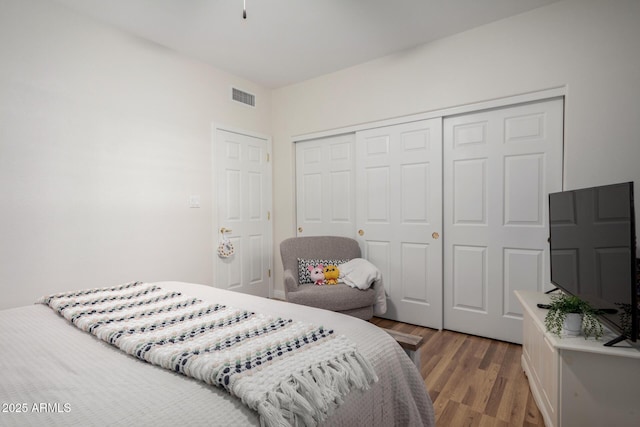 bedroom with a closet, visible vents, and wood finished floors