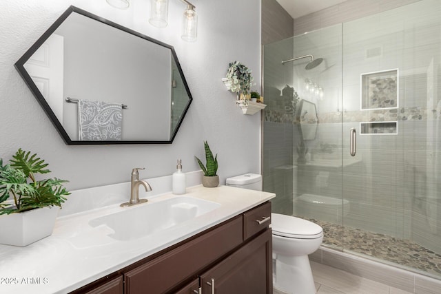 full bathroom featuring a stall shower, vanity, and toilet