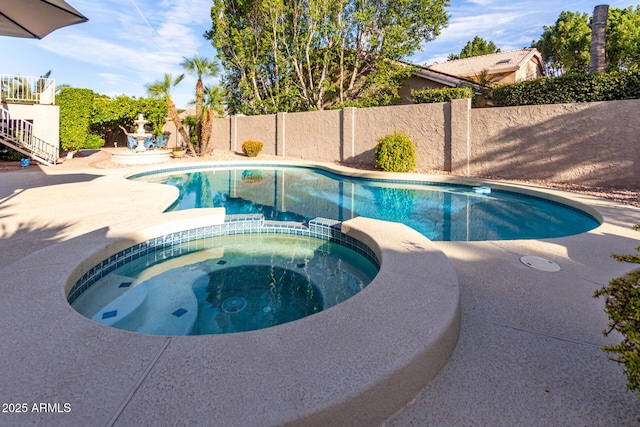 view of swimming pool featuring a pool with connected hot tub and a fenced backyard