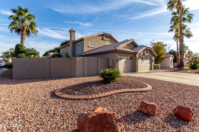 view of home's exterior with stucco siding, concrete driveway, fence, a garage, and a tiled roof