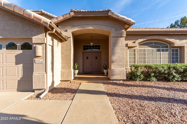 doorway to property featuring a garage and stucco siding