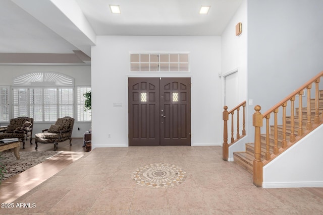 entryway with baseboards, a high ceiling, and stairway